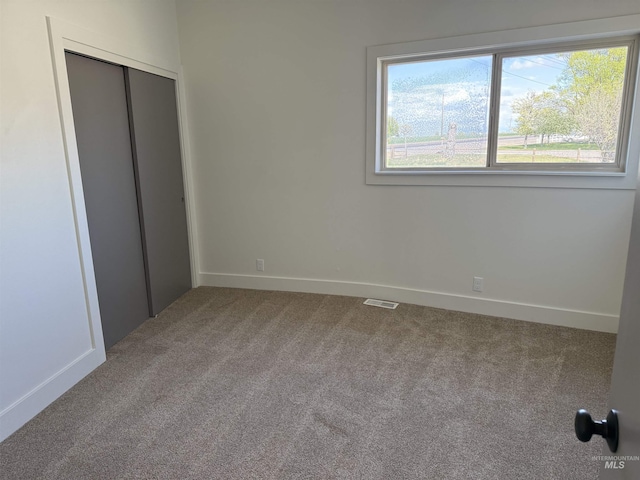 unfurnished bedroom with a closet, baseboards, carpet flooring, and visible vents