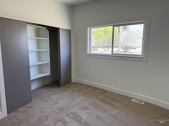unfurnished bedroom featuring carpet floors, baseboards, visible vents, and a closet