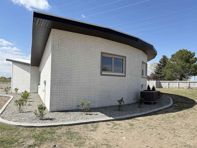 view of home's exterior featuring brick siding, central AC, and fence