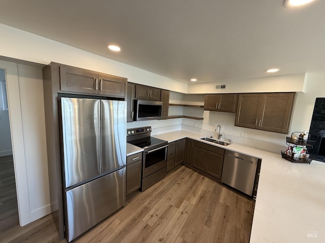 kitchen with open shelves, appliances with stainless steel finishes, a sink, light wood-type flooring, and visible vents