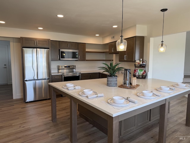 kitchen featuring light countertops, appliances with stainless steel finishes, wood finished floors, and dark brown cabinets