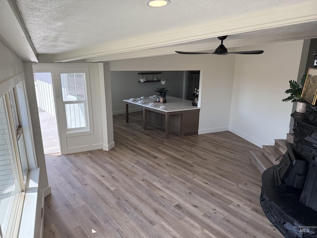 living room featuring a ceiling fan, a textured ceiling, baseboards, and wood finished floors