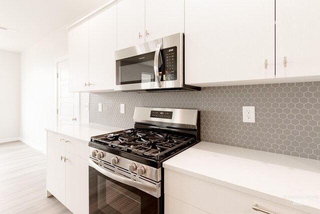 kitchen with stainless steel appliances, white cabinets, and backsplash