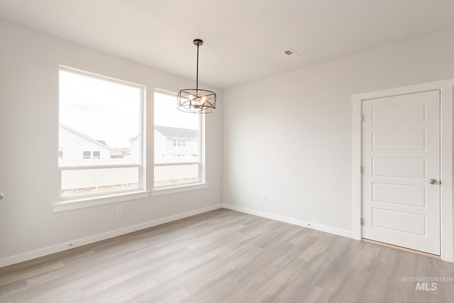 kitchen with appliances with stainless steel finishes, an island with sink, white cabinets, light hardwood / wood-style flooring, and decorative light fixtures