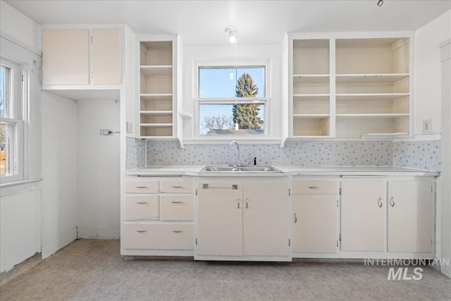 kitchen featuring tasteful backsplash, white cabinetry, and sink