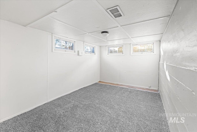 basement featuring plenty of natural light, a paneled ceiling, and carpet flooring