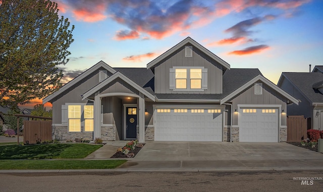 craftsman-style house with fence, board and batten siding, an attached garage, and stone siding