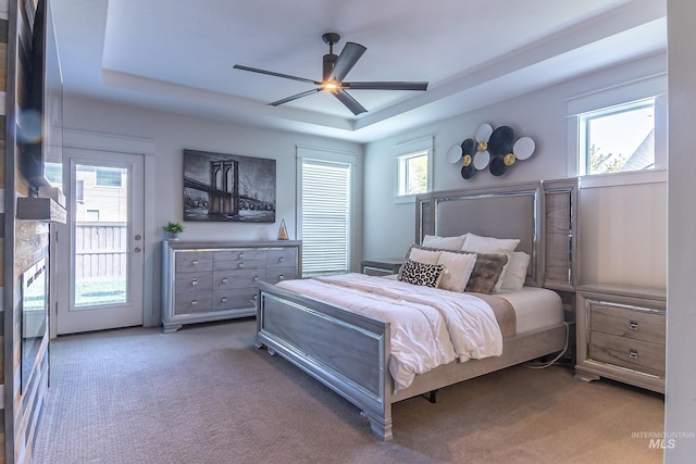 carpeted bedroom with ceiling fan, access to outside, and a raised ceiling