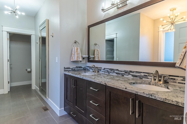 full bath with baseboards, tile patterned floors, a notable chandelier, and a sink