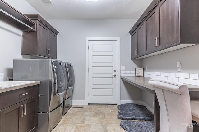 laundry area with stone finish flooring, cabinet space, baseboards, and washer and clothes dryer