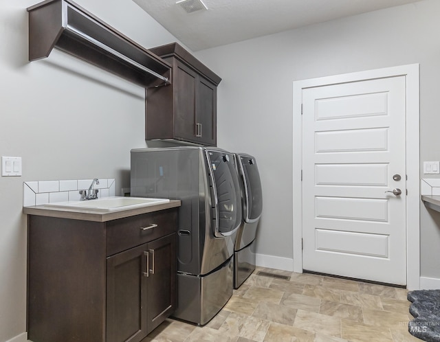 laundry area with cabinet space, washing machine and clothes dryer, a sink, baseboards, and visible vents