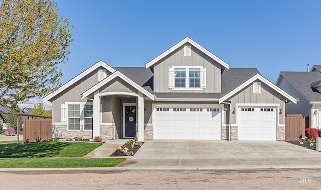 craftsman-style home with fence, board and batten siding, and stone siding