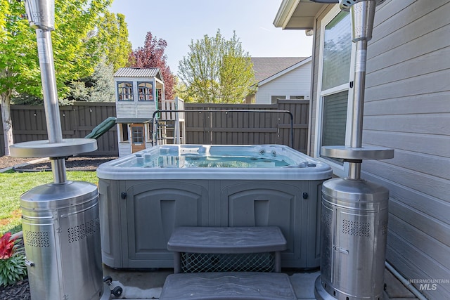 exterior space featuring fence, a hot tub, and a playground