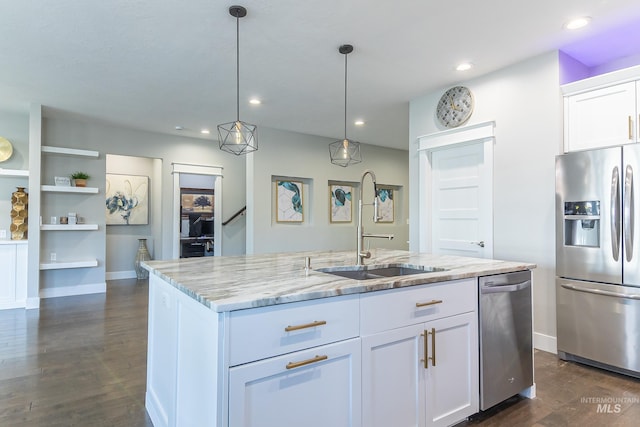 kitchen featuring dark wood finished floors, light stone countertops, stainless steel appliances, a sink, and a center island with sink