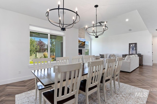 dining area with a stone fireplace, baseboards, and an inviting chandelier