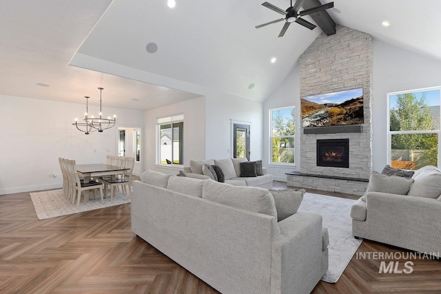 living area with high vaulted ceiling, beamed ceiling, baseboards, a fireplace, and ceiling fan with notable chandelier