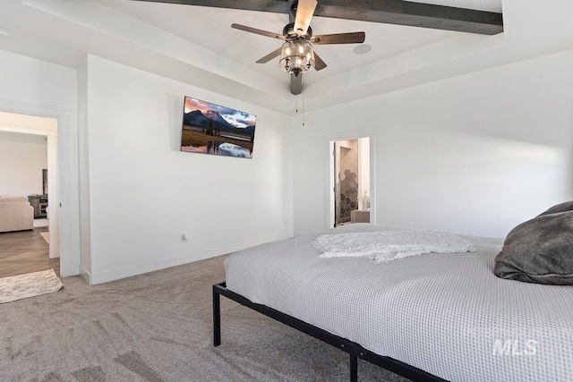 bedroom with a ceiling fan, light carpet, a tray ceiling, and baseboards