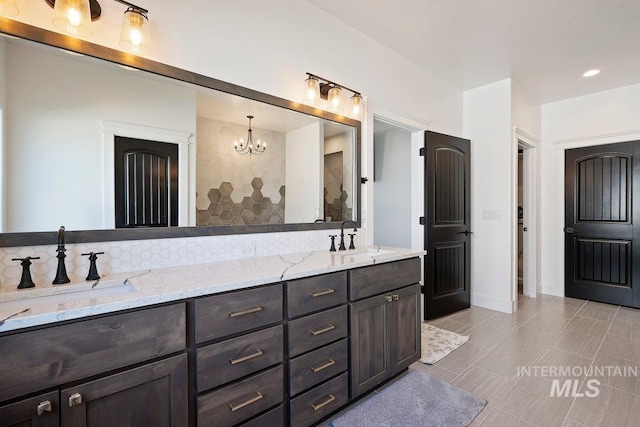 full bath featuring double vanity, a sink, an inviting chandelier, and backsplash