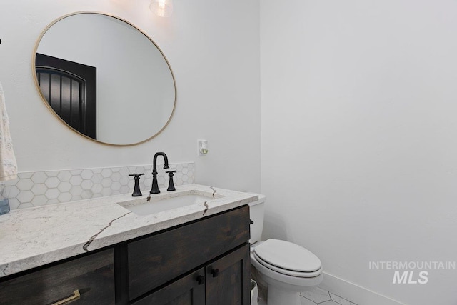 half bath with baseboards, toilet, decorative backsplash, and vanity