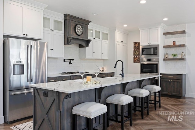 kitchen with open shelves, glass insert cabinets, stainless steel appliances, white cabinets, and decorative backsplash