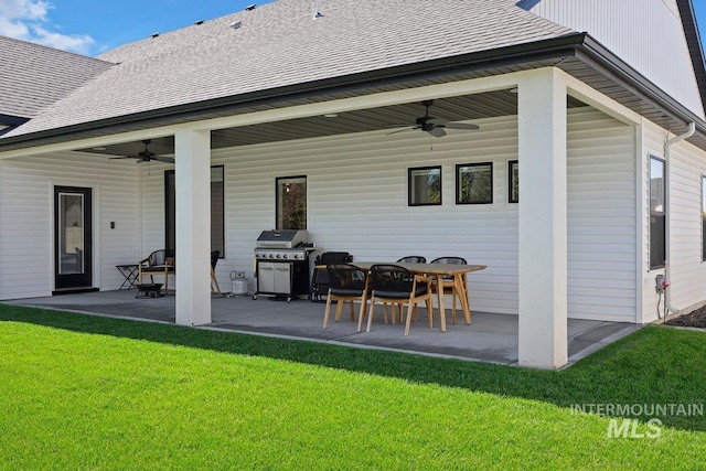 back of property featuring a lawn, roof with shingles, a ceiling fan, and a patio area