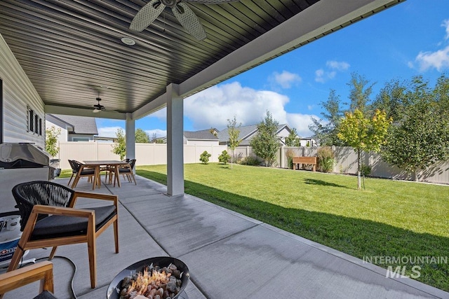 view of patio / terrace with an outdoor fire pit, a fenced backyard, outdoor dining space, and a ceiling fan