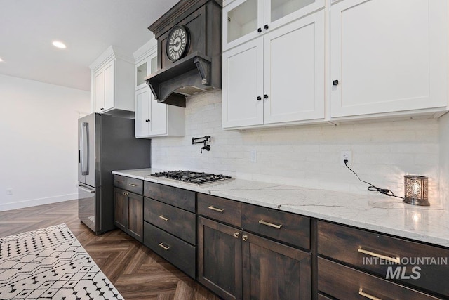 kitchen with dark brown cabinetry, appliances with stainless steel finishes, custom range hood, white cabinets, and decorative backsplash