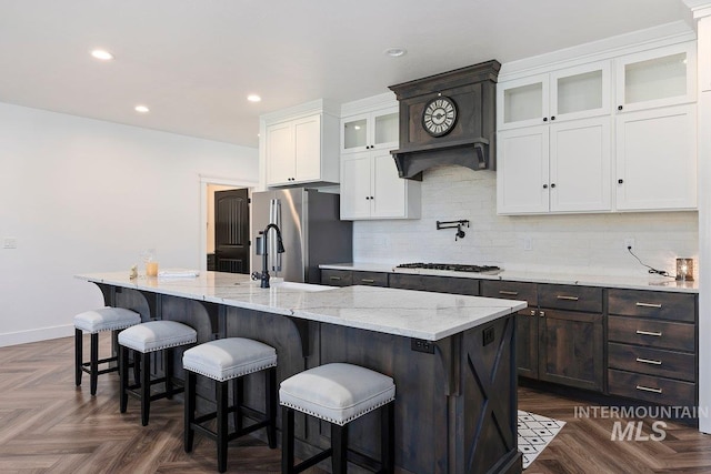 kitchen featuring a sink, white cabinetry, an island with sink, and backsplash