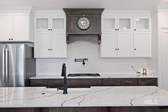 kitchen with freestanding refrigerator, dark brown cabinets, gas stovetop, and white cabinetry