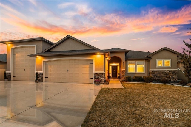 view of front of property featuring an attached garage, stone siding, and stucco siding