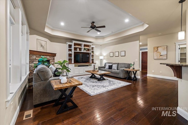 living room featuring visible vents, a ceiling fan, a raised ceiling, and dark wood-type flooring