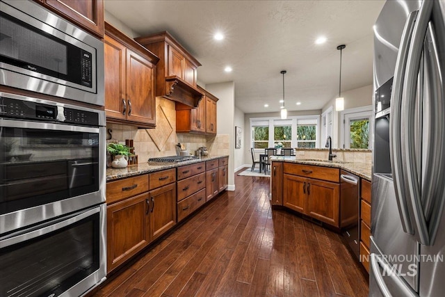 kitchen featuring a peninsula, brown cabinetry, appliances with stainless steel finishes, and a sink