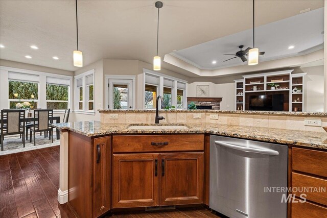 kitchen with stainless steel dishwasher, a healthy amount of sunlight, brown cabinets, and a sink