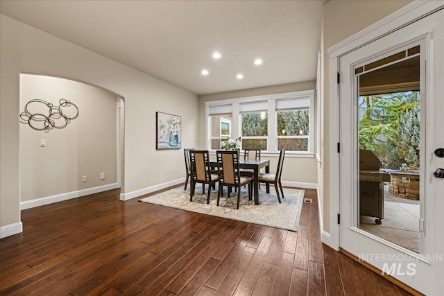 dining area with arched walkways, recessed lighting, baseboards, and dark wood-style flooring