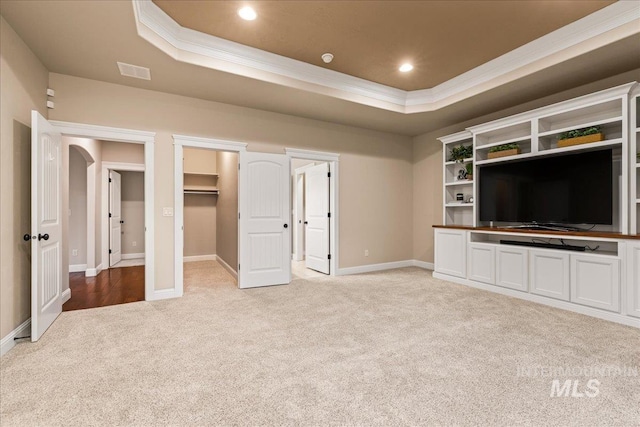 unfurnished living room with a tray ceiling, recessed lighting, light colored carpet, and ornamental molding