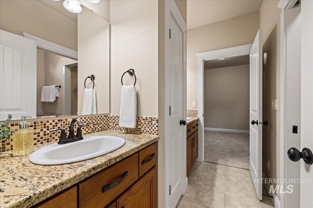 bathroom featuring tile patterned floors, decorative backsplash, vanity, and baseboards