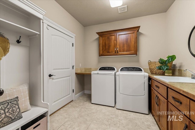 laundry room featuring visible vents, washing machine and dryer, cabinet space, a textured ceiling, and a sink