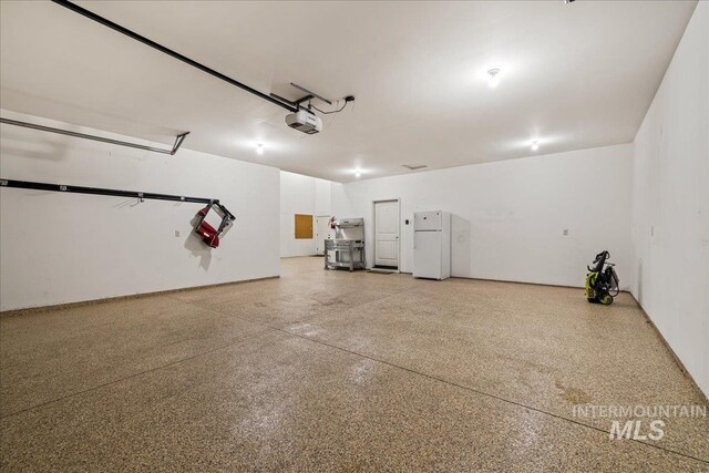 garage with freestanding refrigerator and a garage door opener