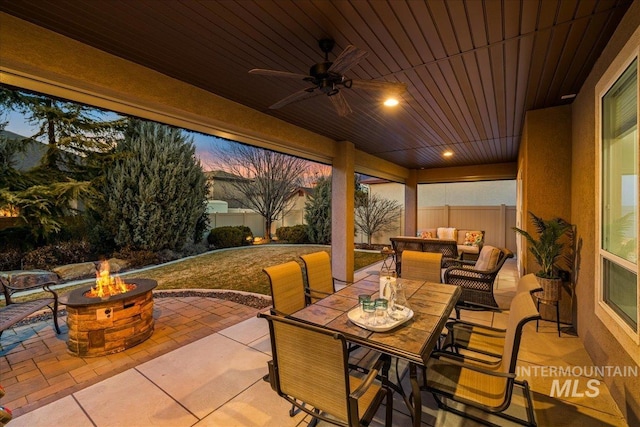 view of patio featuring outdoor dining space, an outdoor living space with a fire pit, ceiling fan, and fence