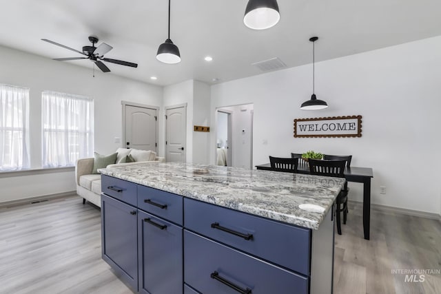 kitchen featuring blue cabinets, ceiling fan, visible vents, and light wood-type flooring