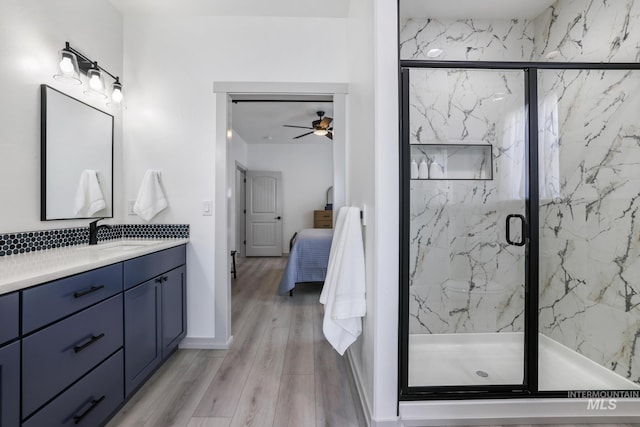 full bath with a marble finish shower, wood finished floors, a ceiling fan, ensuite bathroom, and vanity