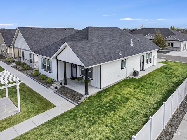 view of front facade featuring central air condition unit, roof with shingles, fence private yard, a front lawn, and board and batten siding