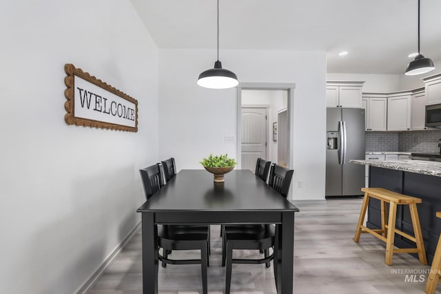 dining space featuring light wood finished floors and baseboards