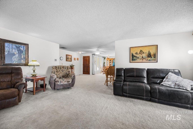 living room with ceiling fan, carpet flooring, and a textured ceiling