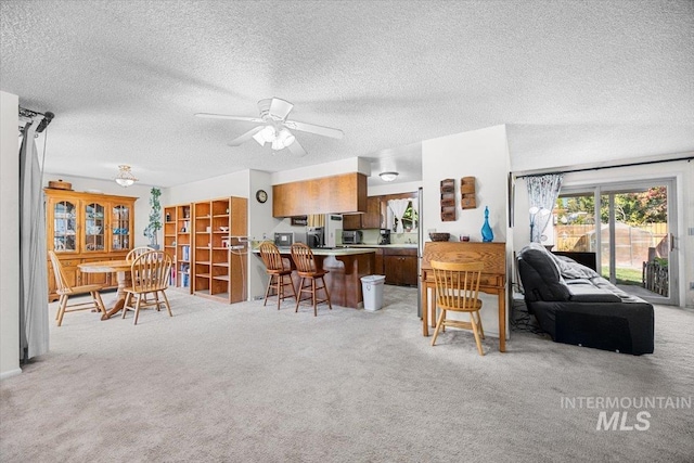 living room featuring ceiling fan, light colored carpet, and a textured ceiling