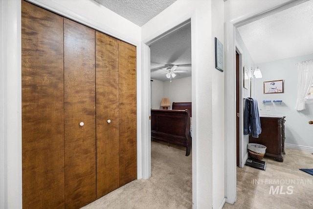 hallway featuring light carpet and a textured ceiling