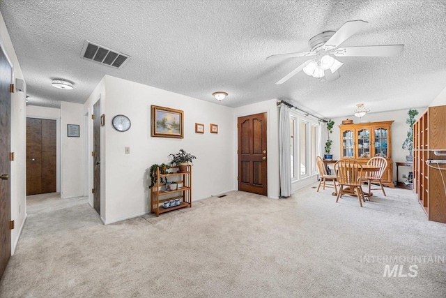 interior space with ceiling fan and light carpet