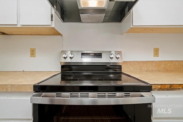 1919 S Banner St, Nampa, ID 83686 - kitchen featuring stainless steel range with electric stovetop, light countertops, white cabinetry, and wall chimney exhaust hood