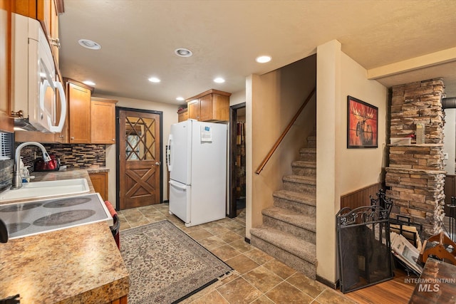 kitchen with stone finish floor, tasteful backsplash, light countertops, recessed lighting, and white appliances