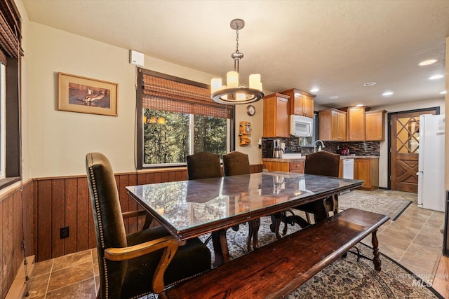 dining room with wooden walls, a notable chandelier, a wainscoted wall, recessed lighting, and stone finish flooring